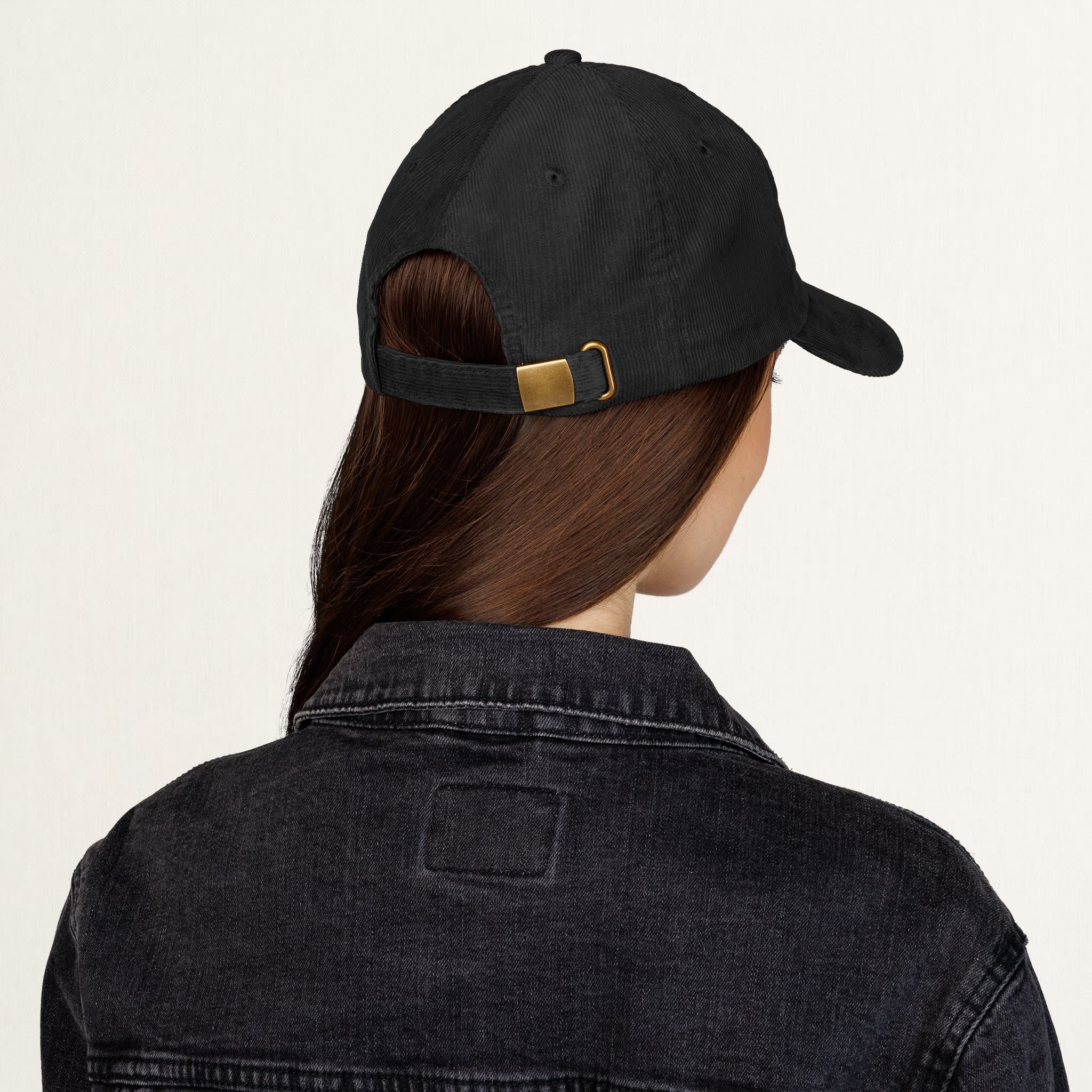 Back view of a black corduroy Raised on Trails cap showing the adjustable metal buckle closure