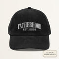 Personalized black corduroy dad cap embroidered with FATHERHOOD EST YEAR — front view