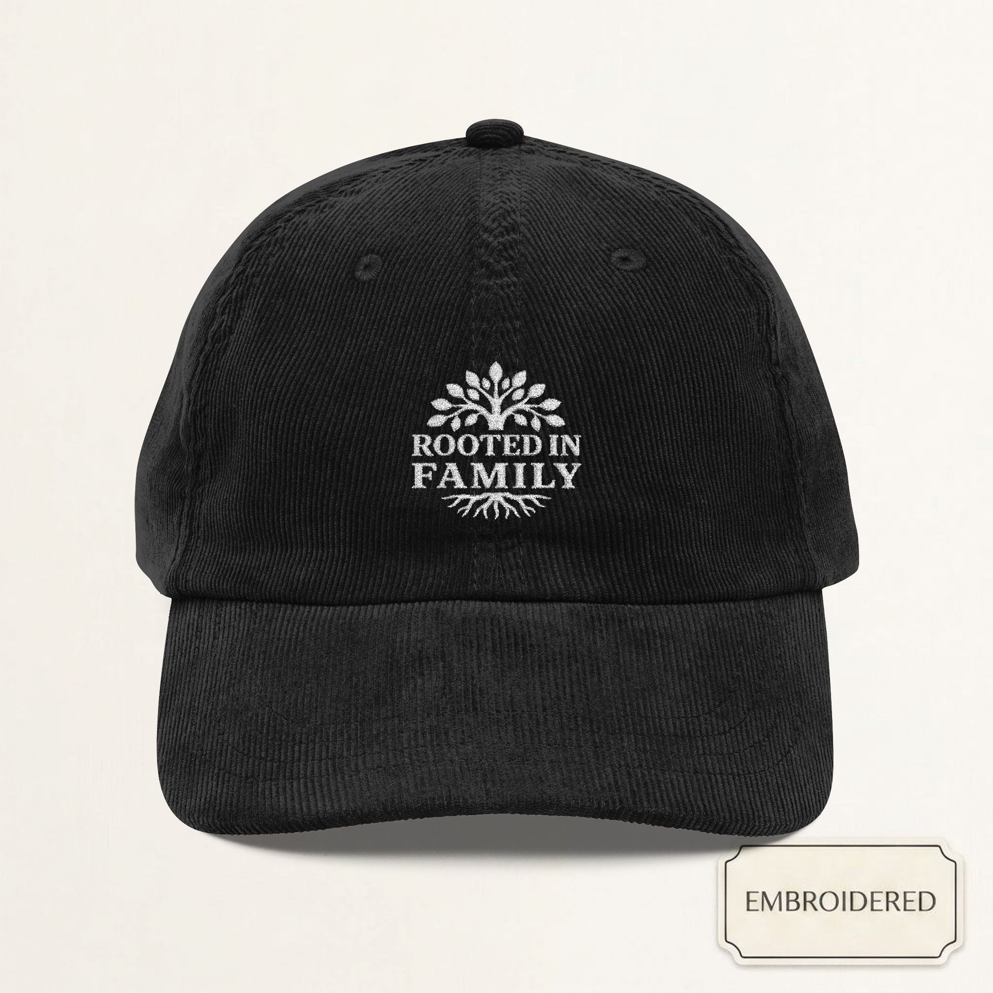 Black corduroy dad cap with small off-white embroidered ROOTED IN FAMILY text on the front panel
