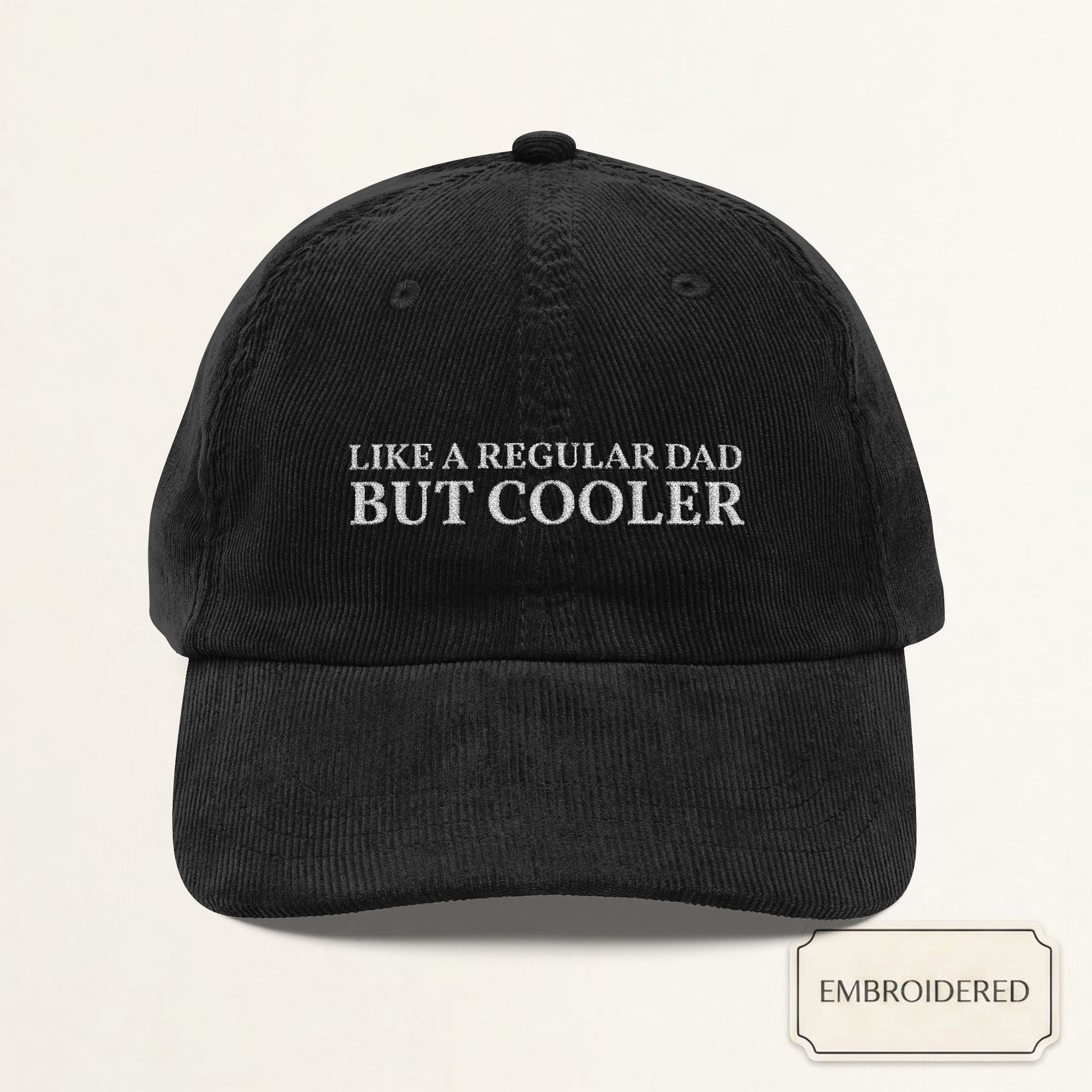 Black corduroy dad cap with REGULAR DAD BUT COOLER off-white embroidery — front view